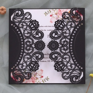 Detail of laser-cut black lace wedding invitation with floral printed insert card