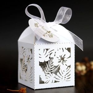 Close-up of white laser-cut floral wedding candy box with thank you tag and ribbon