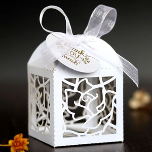 Detail of laser-cut rose patterns on a white candy box with a silk ribbon and tag