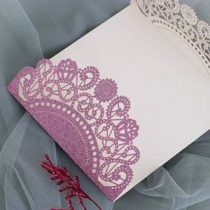 Detail of laser-cut lace edge with purple glitter on elegant wedding invitation card
