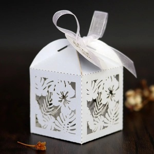 Detailed laser-cut leaf pattern on white wedding favor box with organza ribbon