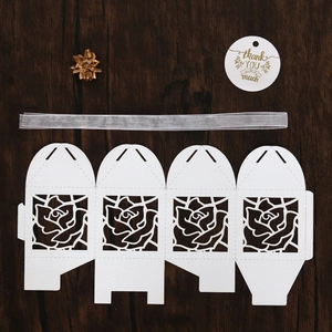 Detail of white laser-cut rose candy box template with silver ribbon and thank you tag