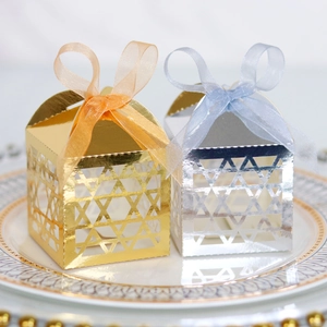 Close-up of laser-cut gold and silver favor boxes with elegant organza ribbons