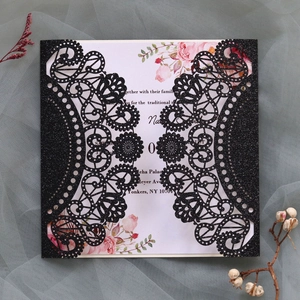 Intricate laser-cut black glitter wedding invitation with floral insert and lace pattern