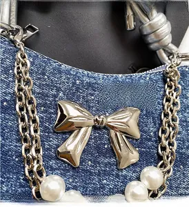 Detailed macro view of denim blue fabric with silver bow and pearl chain strap