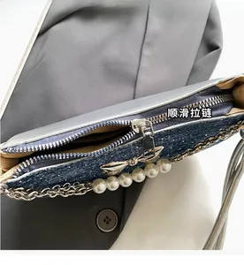 Close-up of smooth metal zipper and pearl chain on dark blue denim bow shoulder bag