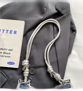 Detail of blue denim shoulder bag featuring silver faux-leather handles and metal hardware