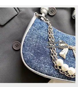 Detail of blue denim shoulder bag featuring silver bow, metal chain and white pearls