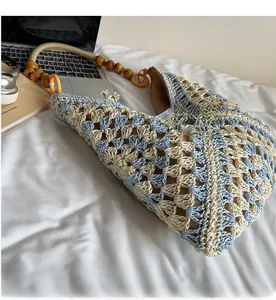 Detail of blue and beige woven tote bag with hollow patterns and wood bead strap accents