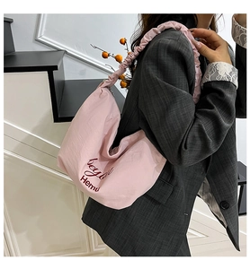 Close-up of pink crescent nylon bag with ruched shoulder strap and red embroidery detail