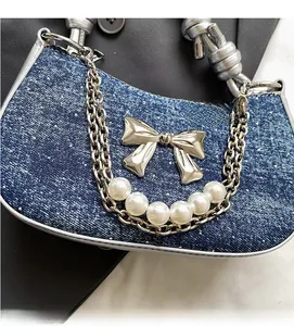 Detail of blue denim shoulder bag featuring silver bow metal and large white pearls