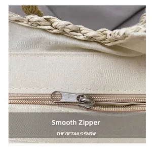Detailed close-up showing smooth zipper and woven straw handle on beige canvas tote bag