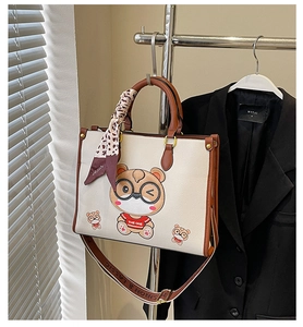 Detail of cream tote bag with bear print, brown handles and leopard print silk scarf