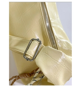 Close-up of cream crocodile pattern leather bag with silver metal zipper and buckle