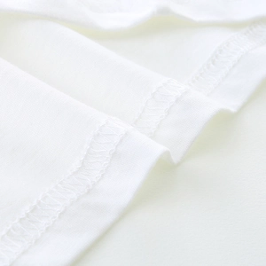 Detailed view of professional overlock stitching on white cotton boys' t-shirt fabric