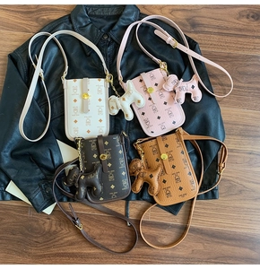 Close-up of four mini bear-pattern crossbody bags with matching dog-shaped charms