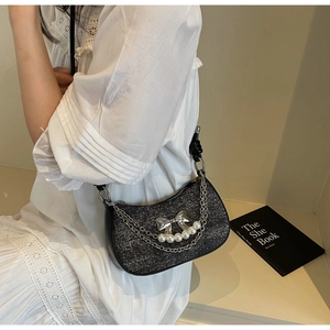 Detail of black glitter half-moon underarm bag with silver bow and pearl chain