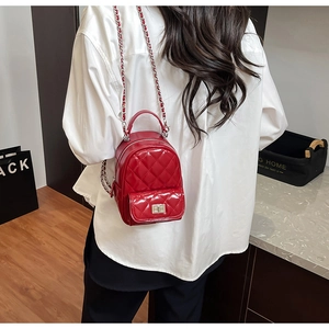 Detail of red quilted mini backpack in glossy patent leather with silver chain strap