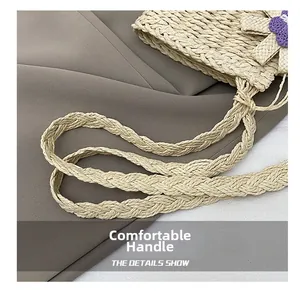 Detail of woven straw tote bag featuring purple crochet flowers and sturdy braided handles