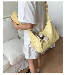 Detail of light yellow crocodile pattern hobo bag with a cute white bear pendant