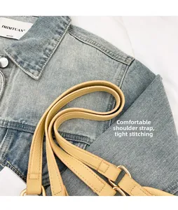 Détail macro d'une bandoulière en cuir grainé jaune avec boucles dorées et coutures précises