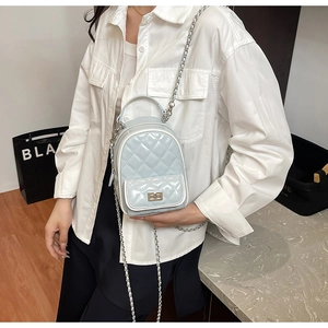 Detail of light blue quilted mini bag with silver chain strap and metal lock closure