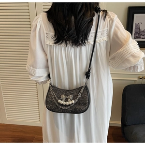 Chic black glitter half-moon crossbody bag with silver bow and pearl chain on a model