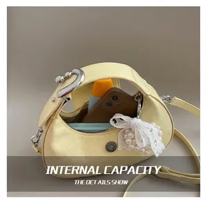 Internal capacity of yellow pleated crescent bag with metal handle and pearl bow detail