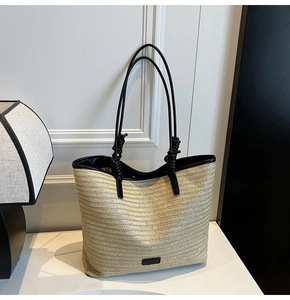 Detail of woven straw tote bag featuring black trim and elegant knotted shoulder straps