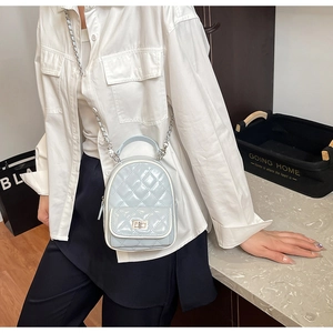 Close-up of quilted light blue mini backpack with silver chain strap and metal turn-lock