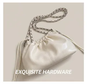 Detail of ivory leather bucket bag featuring woven silver chain strap and drawstring closure