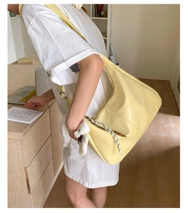 Detail of pale yellow hobo bag with crocodile texture and cute white bear charm