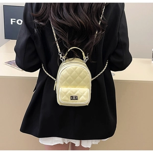 Quilted yellow mini backpack with chain strap on a black blazer for a stylish contrast