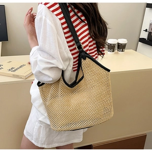 Détail du sac cabas en paille tissée avec anses en cuir noir et finitions soignées