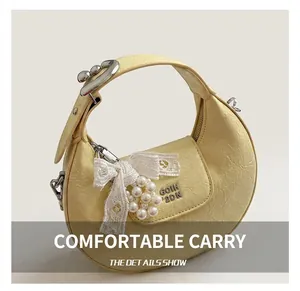 Detail of yellow crescent bag featuring pearl bow charm and lychee texture PU leather
