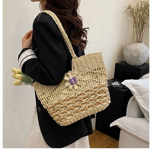 Detailed close-up of handmade woven flowers and hollow knit texture on a large straw tote bag