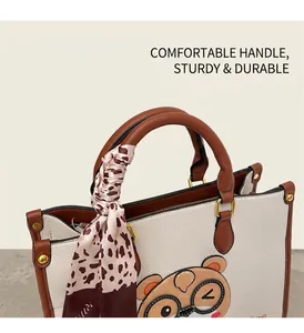 Close-up of white lychee leather tote bag with cute bear patch and silk scarf handle