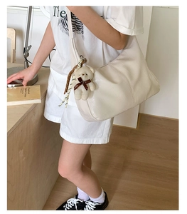 Close-up of cream white dumpling bag with crocodile texture and cute love bear charm
