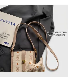 Close-up of beige crossbody phone bag featuring teddy bear print and adjustable strap