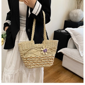 Close-up of a woven straw tote bag featuring wavy patterns and purple flower charm