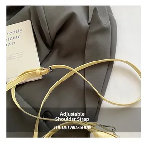 Close-up of adjustable beige leather bag strap with polished silver metal buckle and hook
