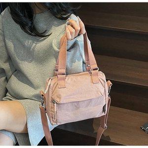 Detailed view of the lotus pink nylon bucket bag with wide strap and zip pocket