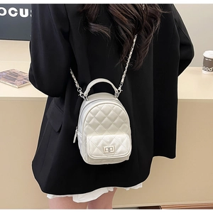 Detail of white quilted mini backpack with metal twist lock and chain shoulder strap