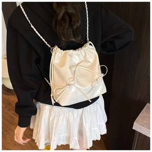 Detail of cream white bucket bag with 3D bows and metal chain strap on model