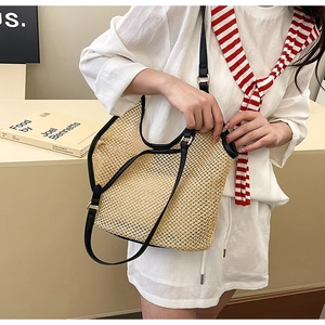 Détail du sac cabas en paille tissée ajourée avec lanières en cuir noir pour l'été