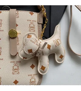 Detail of beige phone bag with Keddy Bear pattern and puppy charm accessory