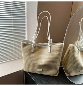 Detail of hand-woven straw tote with white faux leather handles and knotted texture