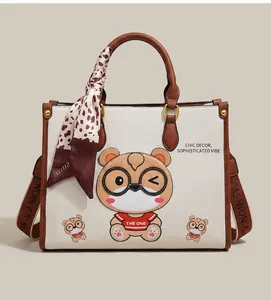 Detail of white litchi pattern tote bag with brown leather trim and bear print