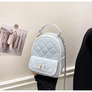 Detail view of light blue quilted mini backpack with silver metal chain and twist lock