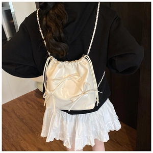 Close-up of white glossy drawstring backpack with bow details and metal chain straps